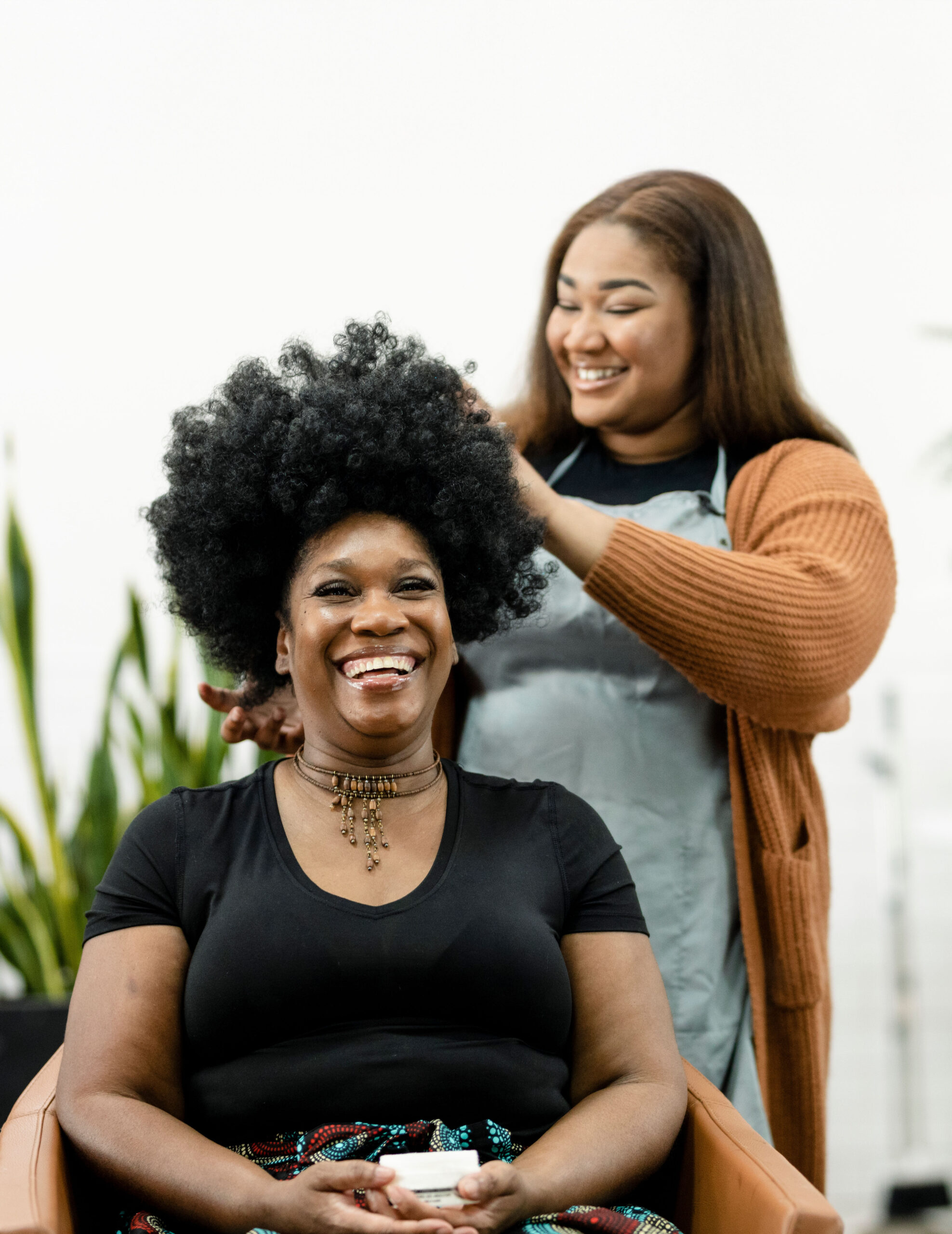 Hair stylist laughing and styling a client's curly hair.