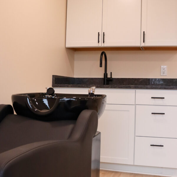 Modern backwash unit with a wash sink, designed for shampooing clients in a spacious salon studio.