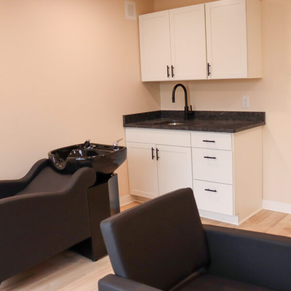 A Classic Studio at Riviera Salon Studios equipped with one stylist chair, one backwash unit, and spacious cabinetry with a granite countertop and wash sink
