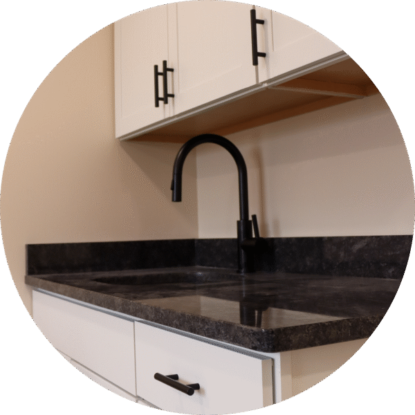 A close-up of a dark granite countertop with a black faucet and spacious cabinetry above.