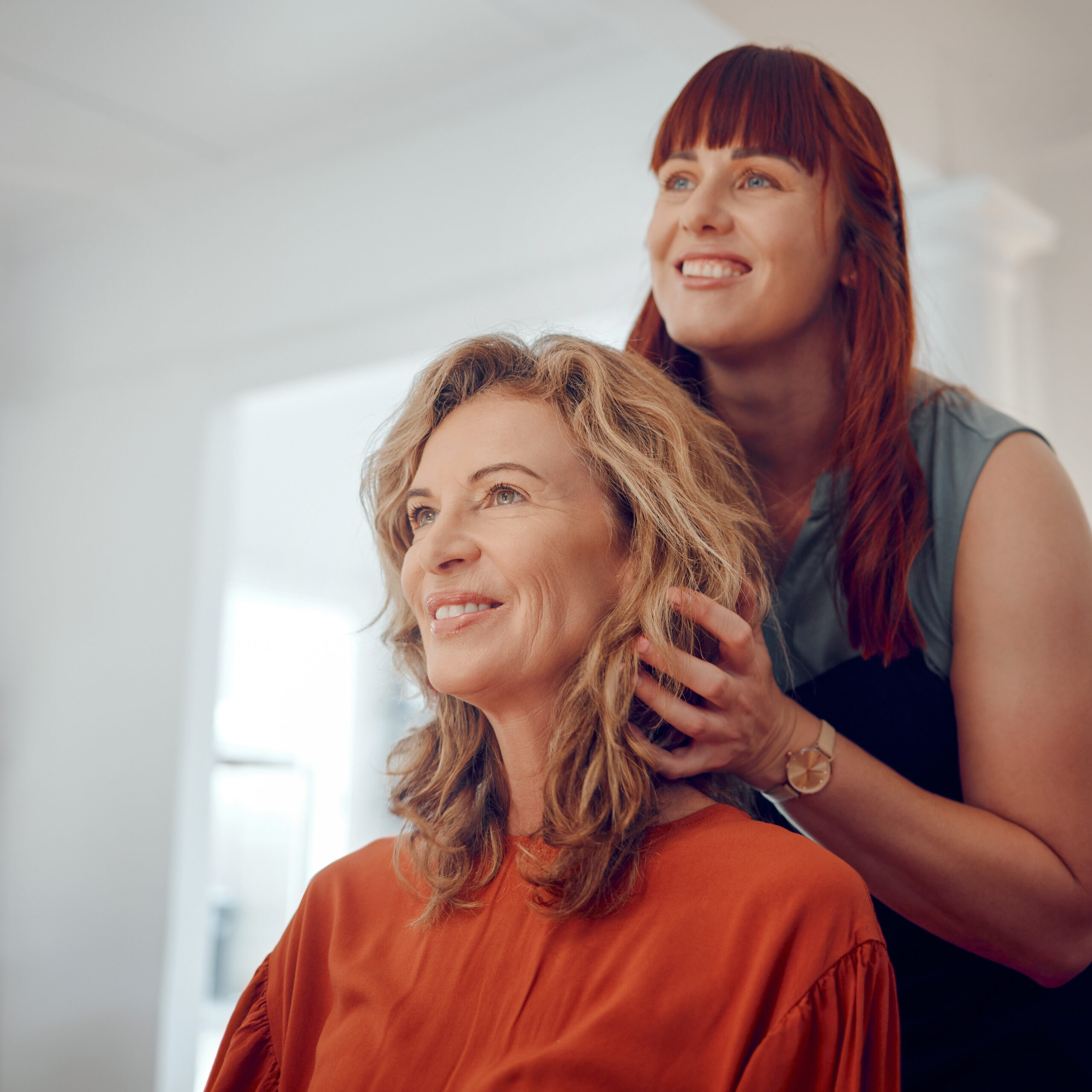 Hair stylist smiling while revealing a new curly haircut to a client in a salon, both looking happy and confident.