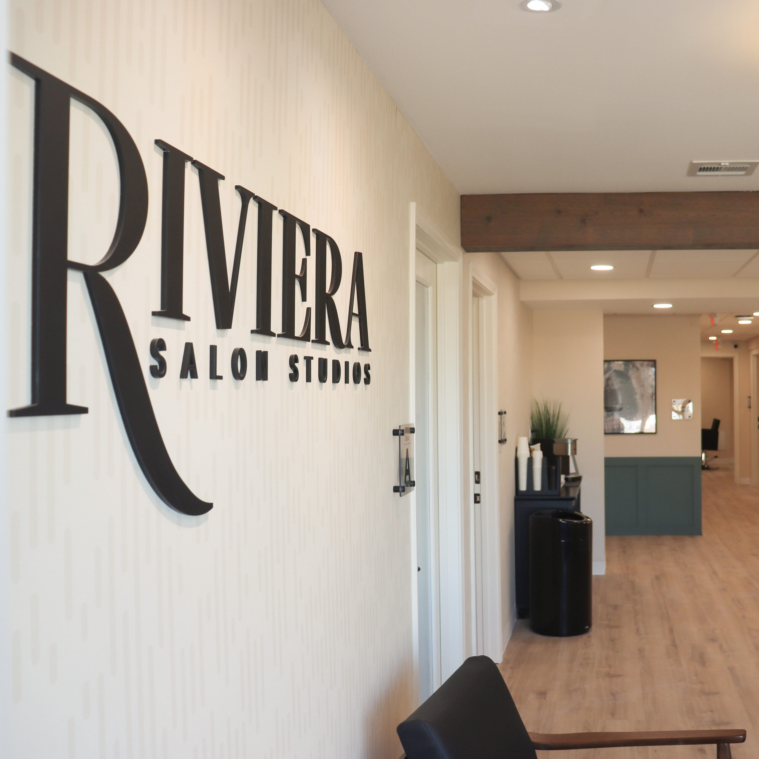Riviera Salon Studios sign displayed in the entryway, with sleek, modern design and a welcoming hallway leading to salon studios.