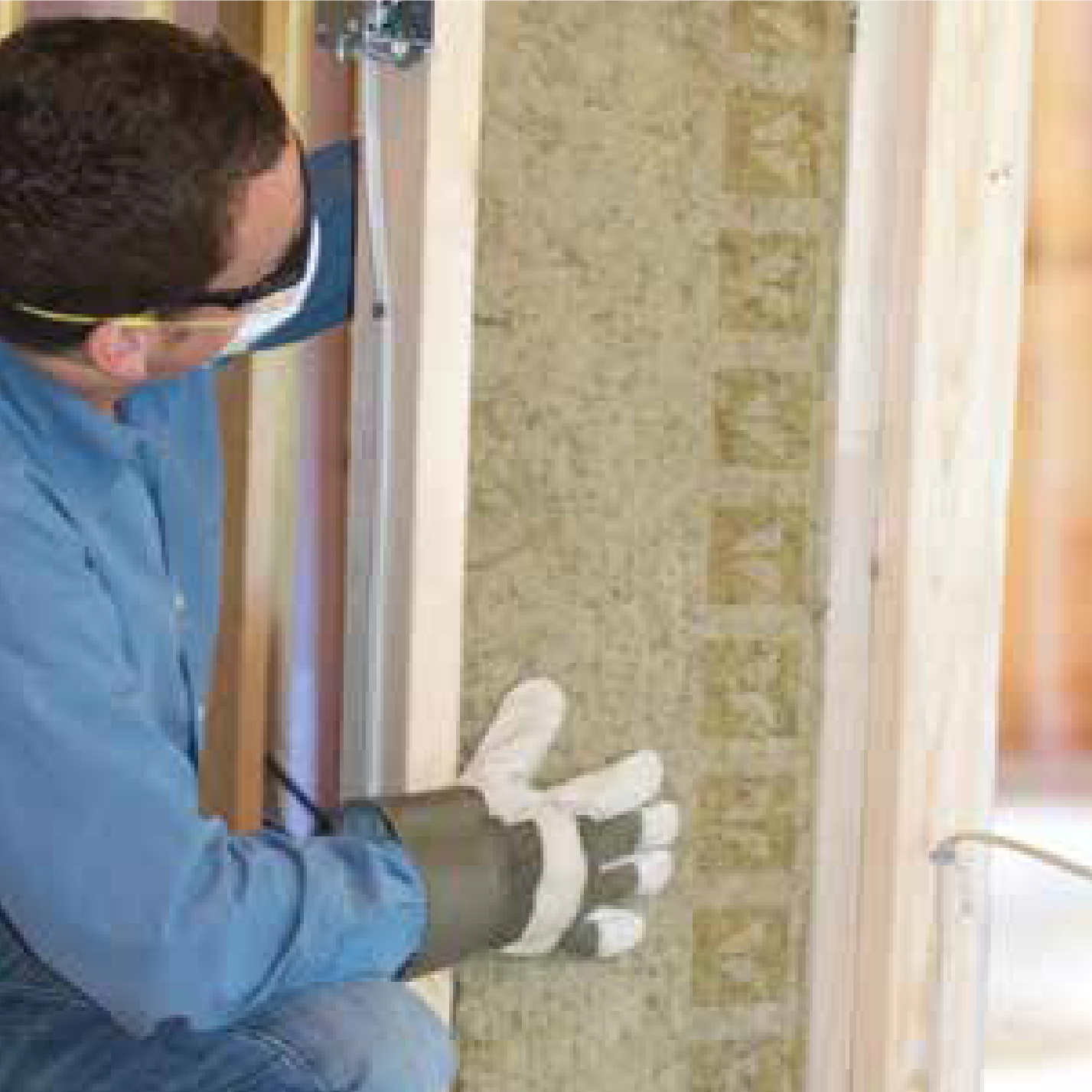 A person installing Rockwool soundproof insulation between wooden studs.