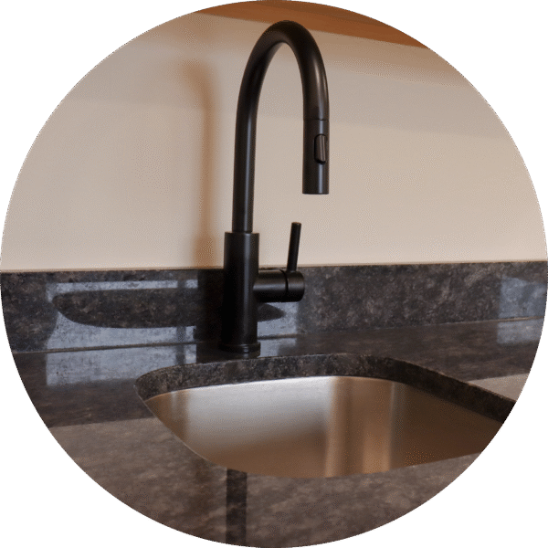 A modern stainless steel wash sink with a sleek black faucet.