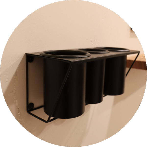 A black wall-mounted holder with multiple compartments, designed for storing hairstyling tools.