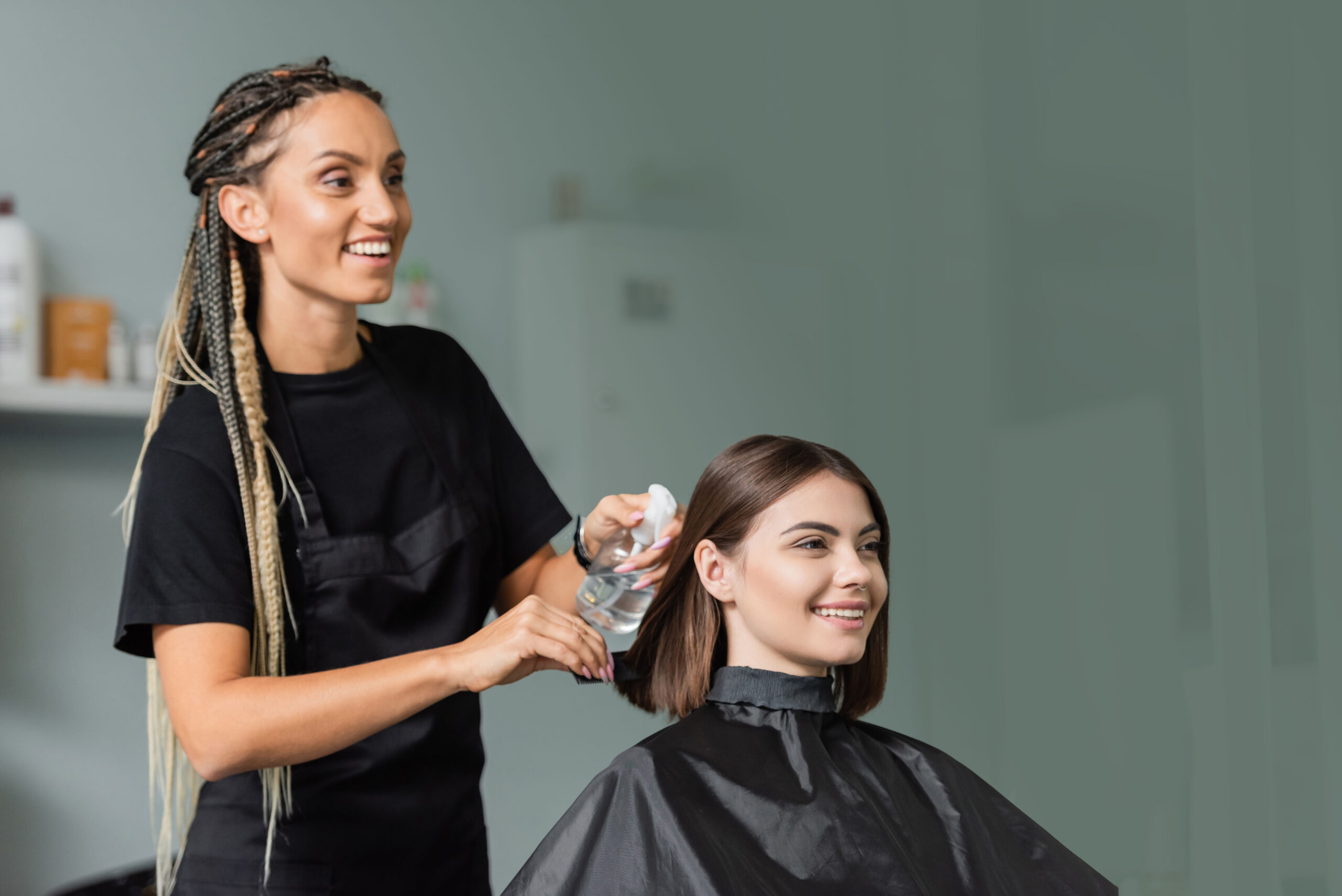 Stylist Spraying Client’s Hair Stylist spraying water on a client's hair, preparing for a trim in a salon.