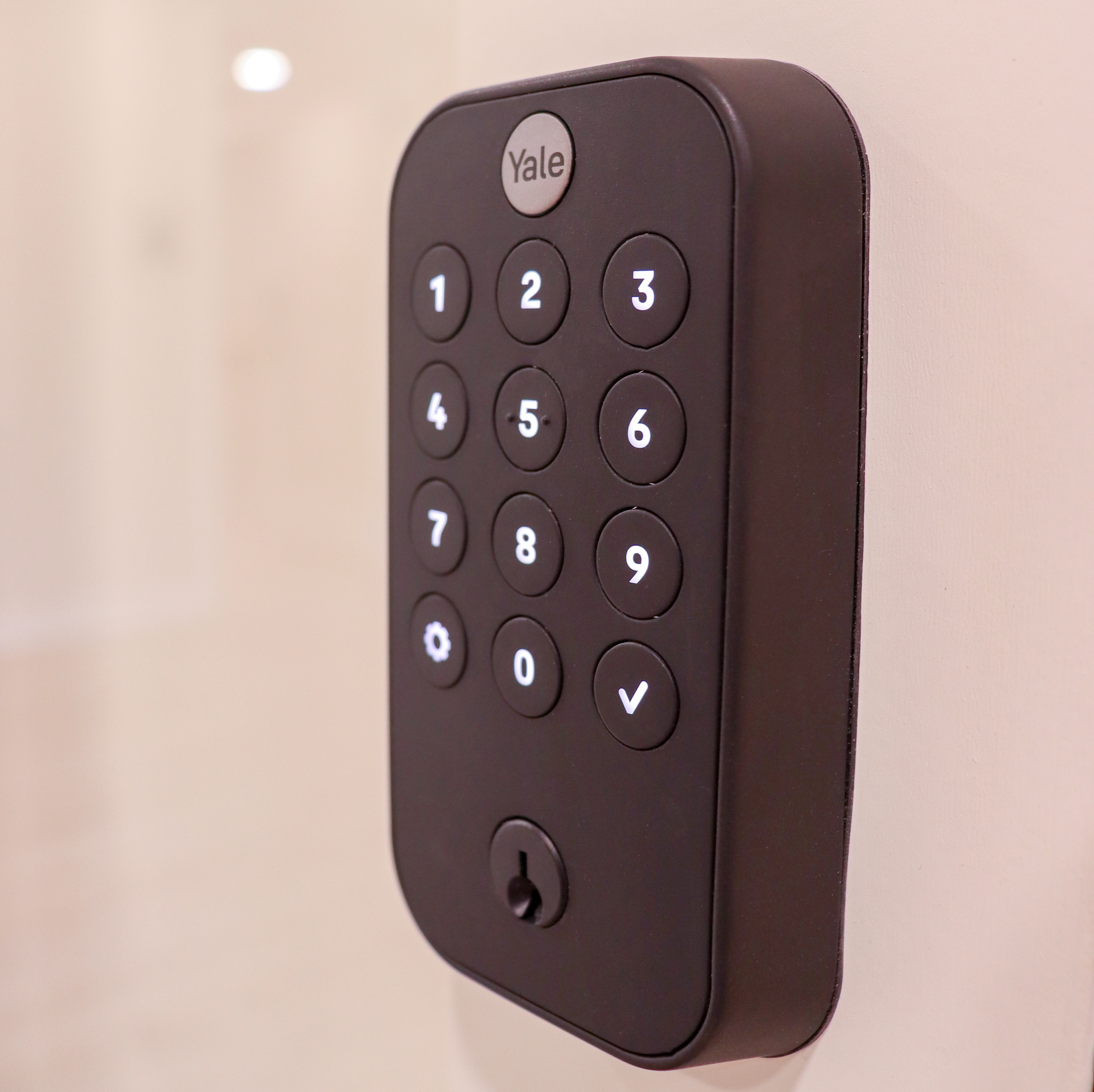 Close-up of a Yale smart lock mounted on a studio door, displaying a keypad with numbers 1-9.